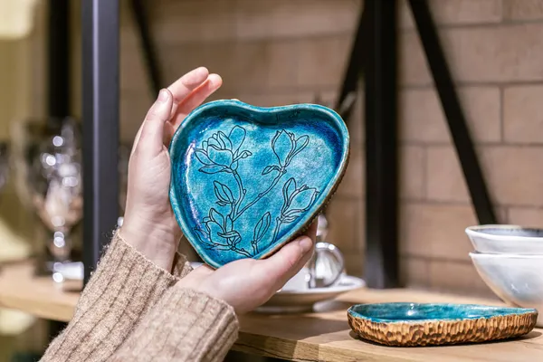 Placa de cerámica en forma de corazón en manos femeninas. — Foto de Stock