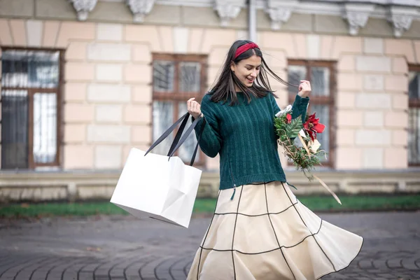 Ung kvinna med julklappar utanför, julshopping. — Stockfoto