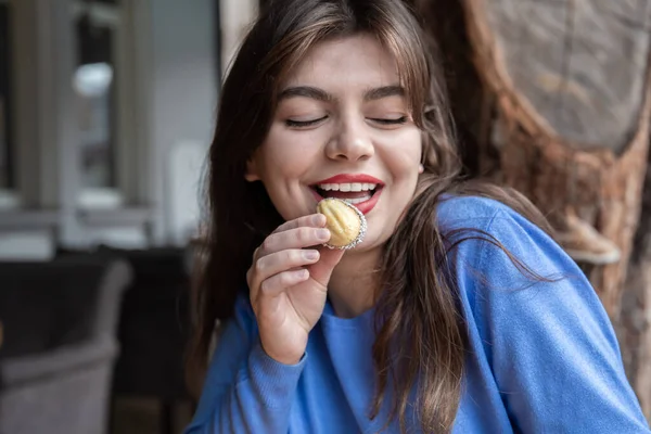 Una joven comiendo galletas de sándwich con forma de nuez. — Foto de Stock