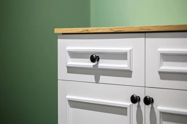 Close-up of a white cabinet with black handles on a green wall background. — Stock Photo, Image