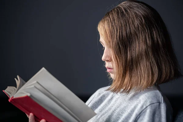 Poważna dziewczynka czytająca książkę, zamazane tło. — Zdjęcie stockowe