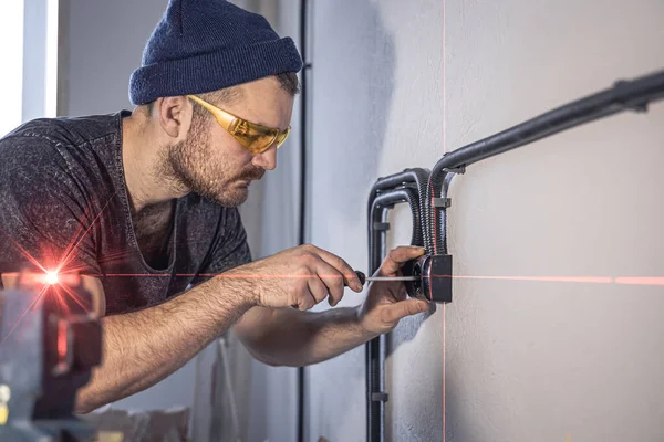 Un electricista está montando tomas eléctricas en la pared blanca en el interior. — Foto de Stock
