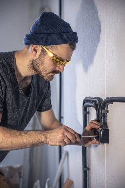 Bir elektrikçi beyaz duvarlara elektrik prizleri takıyor..