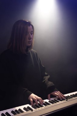 Genç bayan piyanist puslu karanlık bir odada anahtar çalıyor..