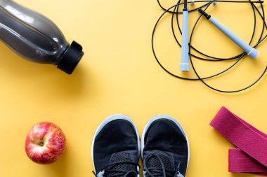 Düz kompozisyon ve sarı arka planda spor ekipmanları.