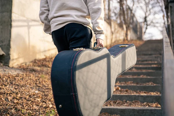 En manlig gitarrist bär ett gitarrfodral utanför. — Stockfoto