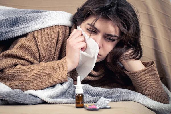Sick young woman with medicines lies in bed, colds and home treatment. — Stock Photo, Image