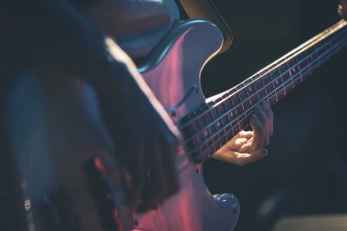 Bas gitar çalan bir adamın yakın çekimi..