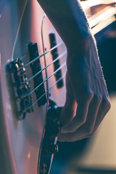 Close-up of a man playing the bass guitar.