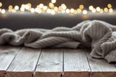 Ahşap bir yüzey ve bokeh ışıkları üzerinde örülmüş elementle samimi bir arkaplan.