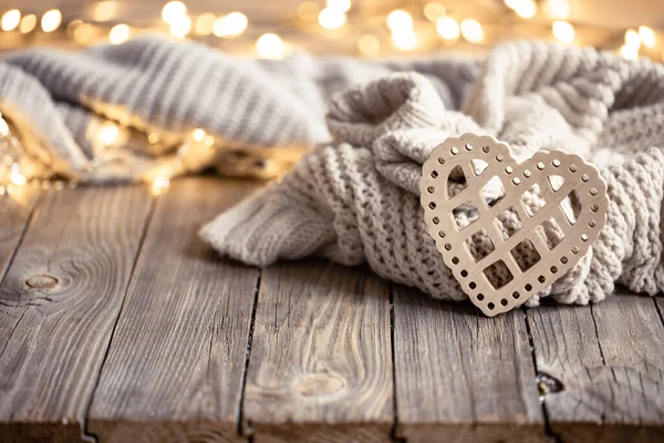 Cozy background with a knitted element, decorative heart and bokeh lights. — Stock Photo, Image