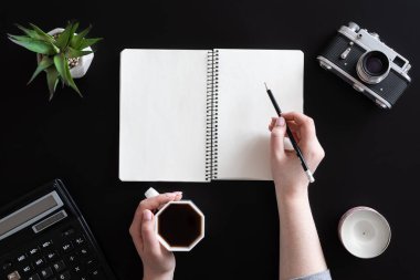 Kadın elleri ve siyah arka planda boş not defteri, düz uzanmış..