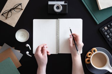 Kadın elleri ve siyah arka planda boş not defteri, düz uzanmış..