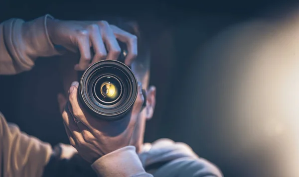 A man photographer with a camera takes a photo in the dark, copy space. — Stock Photo, Image