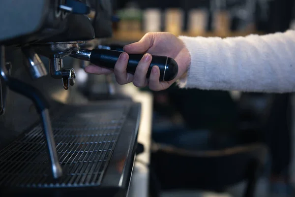 Una mano femenina sostiene un soporte en una cafetera profesional. — Foto de Stock