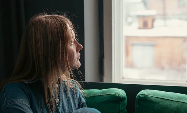 사랑 스러운 한 젊은 여성 이 창가 소파에 앉아 있습니다. — 스톡 사진