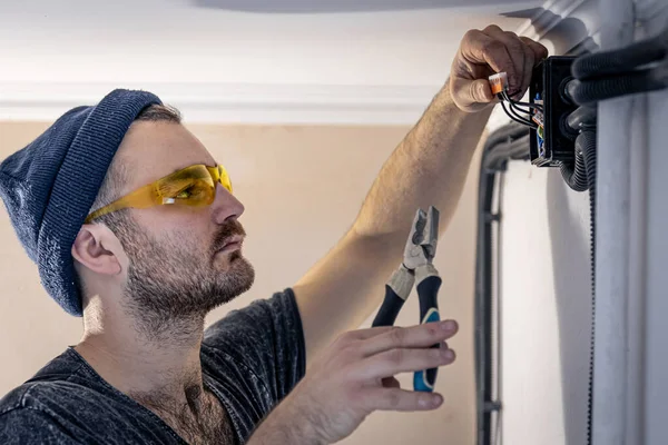 An electrician is mounting electric sockets on the white wall indoors. — Stock Photo, Image