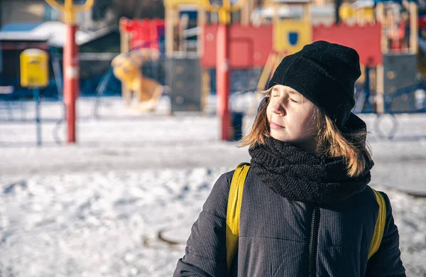 Seorang gadis kecil dipanaskan di bawah matahari dalam cuaca musim dingin yang dingin. — Stok Foto