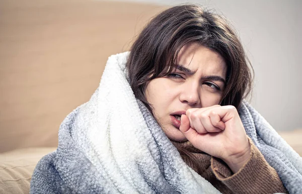O tânără bolnavă tuşeşte, înfăşurată într-o pătură. — Fotografie, imagine de stoc