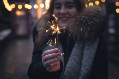 Karanlıkta genç bir kadının ellerinde yanan maytaplar..