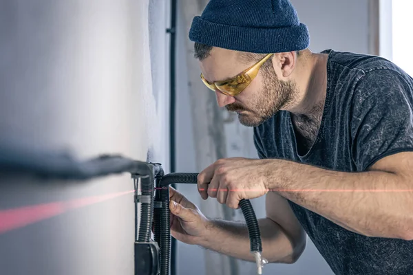 An electrician is mounting electric sockets on the white wall indoors. — Stock Photo, Image