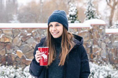 Karlı havada termosu olan mutlu genç bir kadın..