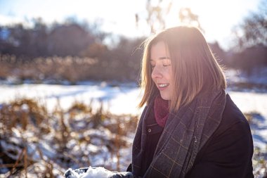 Ellerinde karla kışın yürüyüşe çıkan mutlu genç bir kadın..
