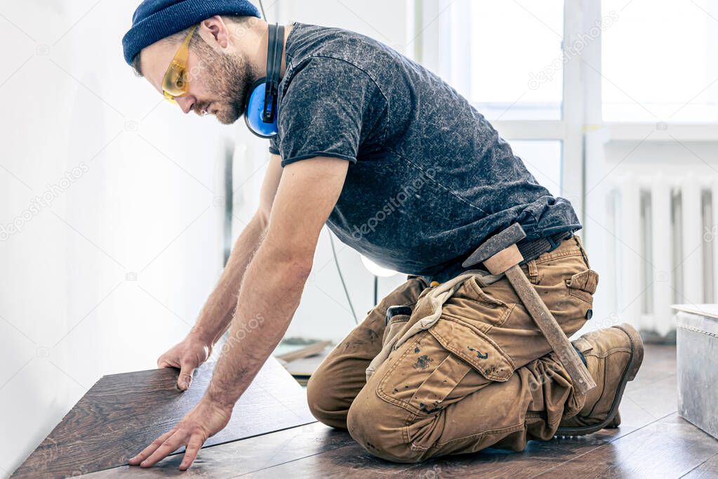 A male worker puts laminate flooring on the floor.