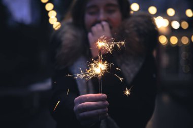 Karanlıkta genç bir kadının ellerinde yanan maytaplar..