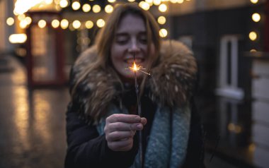 Karanlıkta genç bir kadının ellerinde yanan maytaplar..