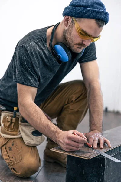 A male worker puts laminate flooring on the floor. — Stock Photo, Image