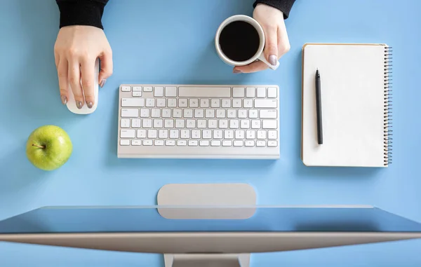 Vista superior, las manos femeninas trabajan en la computadora, fondo azul. — Foto de Stock