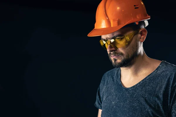 Electricista masculino en casco protector con gafas sobre fondo negro. — Foto de Stock