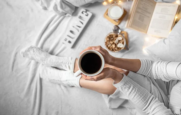 Taza de café en manos femeninas en la cama, vista superior. — Foto de Stock