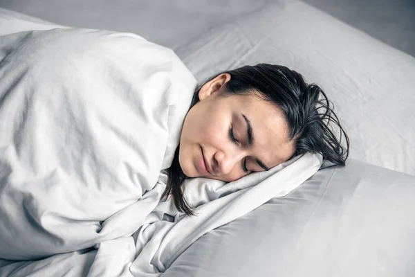 Una hermosa joven duerme en una cama blanca. — Foto de Stock