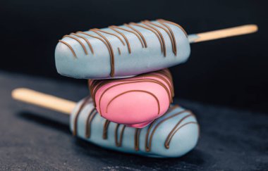 Pembe ve mavi çikolatayla kaplı buzlu dondurma şeklinde tatlı..