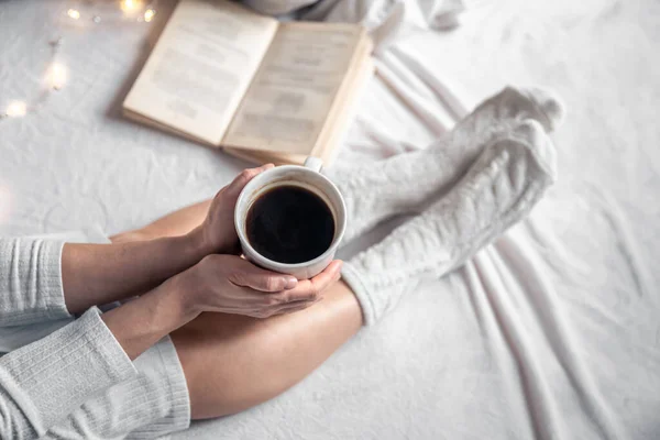 Kaffeebecher in weiblichen Händen im Bett, Draufsicht. — Stockfoto