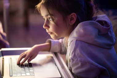 Küçük bir kız geç saatlerde dizüstü bilgisayar kullanıyor..