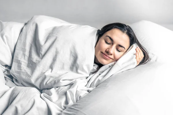 Una hermosa joven duerme en una cama blanca. — Foto de Stock