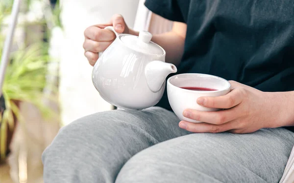 Una taza de té blanco y una tetera en las manos de una mujer. — Foto de Stock