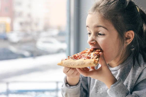 İştah açıcı bir dilim pizzayla küçük bir kızın portresi.. — Stok fotoğraf