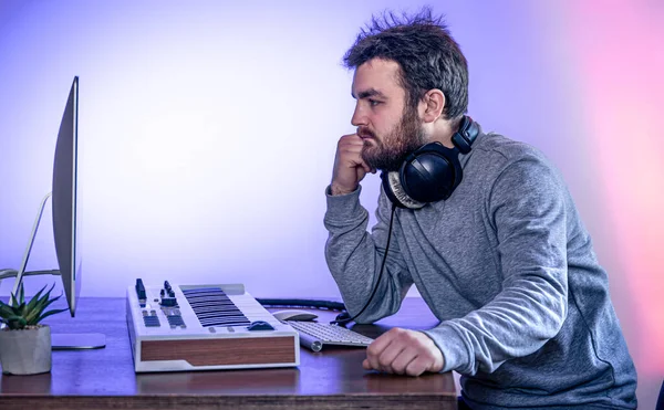 Muž hudebník vytváří hudbu pomocí počítače a klávesnice, hudebník pracoviště. — Stock fotografie