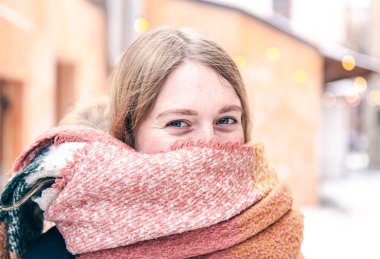 Kışın atkıya sarılmış genç bir kadının portresi..