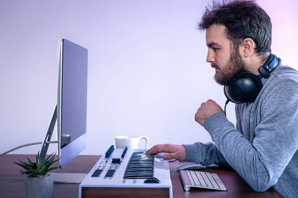 Mannelijke muzikant maakt muziek met behulp van computer en toetsenbord, muzikant werkplek. — Stockfoto