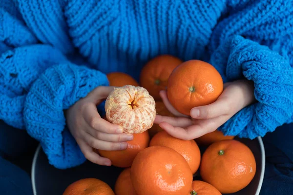 Close-up de uma tangerina nas mãos de uma criança. — Fotografia de Stock