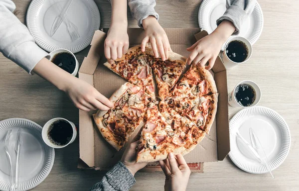 Masadaki karton kutudan pizza dilimleri alan gençler.. — Stok fotoğraf