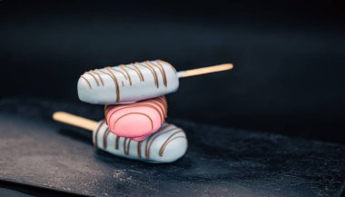 Pembe ve mavi çikolatayla kaplı buzlu dondurma şeklinde tatlı..