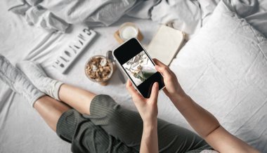 Bir kadın yatakta yatarken kahvaltının fotoğrafını çeker..