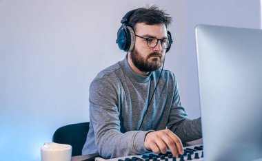 Erkek müzisyen bilgisayar ve klavye, müzisyen işyeri kullanarak müzik yaratır.