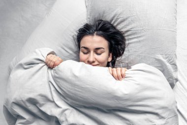 Güzel genç bir kadın beyaz bir yatakta uyuyor..